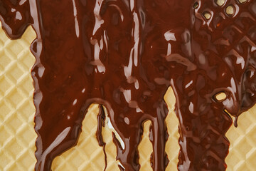 Streams of molten chocolate flowing down a waffle sheet. Close up of the waffle sheet. Pattern wafle texture. Shallow depth of field