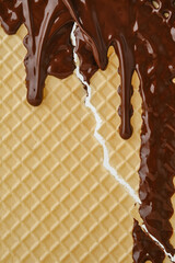 Streams of molten chocolate flowing down a waffle sheet. Close up of the waffle sheet. Pattern wafle texture. Shallow depth of field