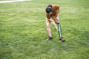 Young man adjusting his prosthetic leg outdoor - Focus on hand holding prosthesis - Powered by Adobe