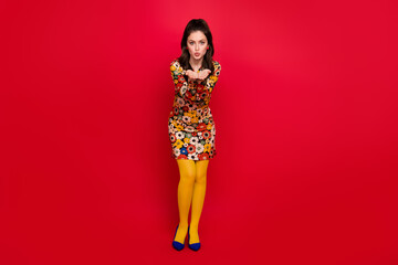 Photo of sweet shiny young lady dressed flower print outfit sending you arms kiss isolated red...