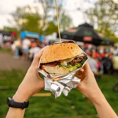 Foto op Canvas Big burger in hands at street food outdoor festival © 9parusnikov