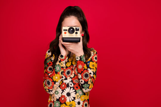 Portrait of attractive cheerful girl using old fashioned cam making capture cadre art isolated over bright red color background