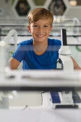 Portrait of smiling caucasian elementary schoolboy sitting at desk in science laboratory
