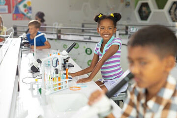 Portrait of african american elementary schoolgirl at desk in science laboratory