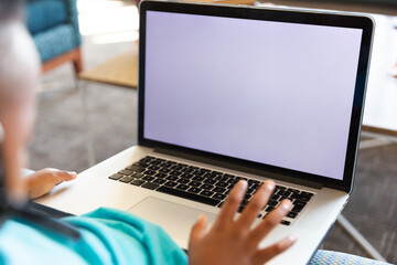 Fototapeta premium Close-up of african american elementary schoolboy using laptop while sitting in school