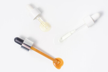 Three pipettes with serum and collagen on white background close-up.