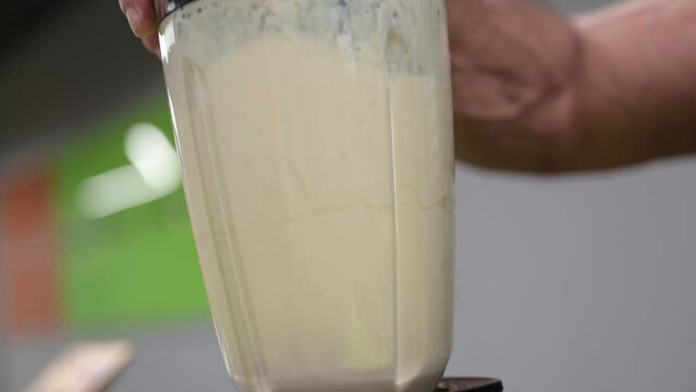 hand of strong sport fitness athlete turn on shaker mixer blender with milk protein gainer after training