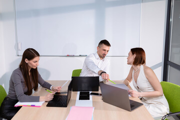 Three colleagues are in the meeting room discussing business projects. Selective focus in the center of the photo