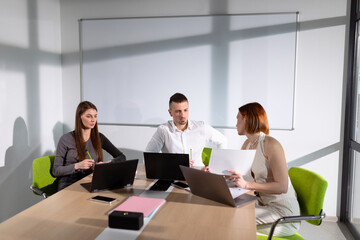 Colleagues in the meeting room communicate about a business project. Selective focus in the center of the photo