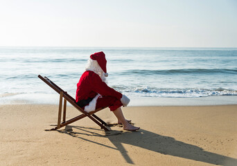 Christmas santa claus sitting on a beach chair.