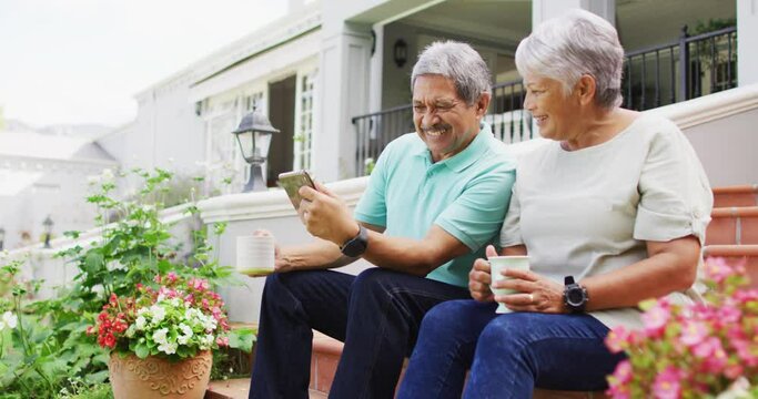 Video of happy biracial senior couple using tablet in garden