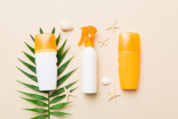 Sunscreen spray bottle. Bottle with sun protection cream and sea shells with tropical green leaf on color background, top view