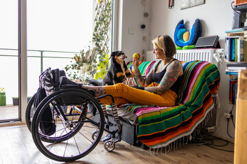 Young woman with disability with her dog at home
