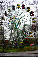 ferris wheel in the center of the park. red and yellow booths. It's a nasty day.