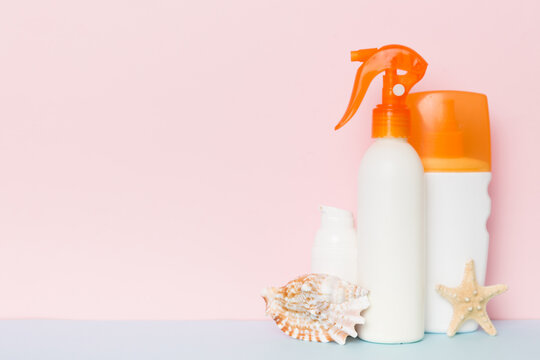 Beach accessories. Moisturiser sunscreen suntan lotion bottle for UVB skincare protection in summer with seashells on colored background. Mock up with copy space