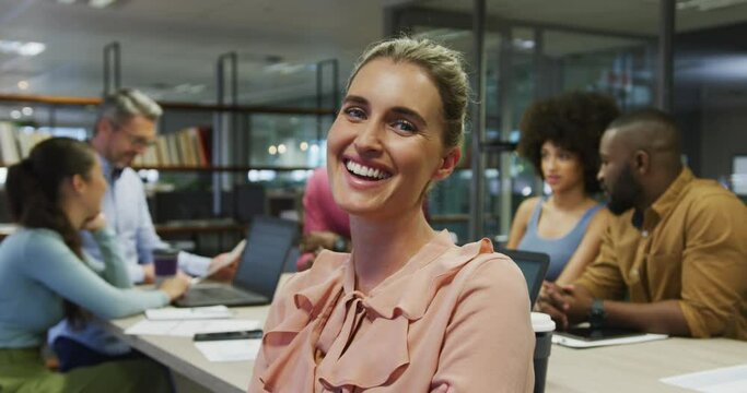 Portrait of caucasian businesswoman smiling over diverse business colleagues talking