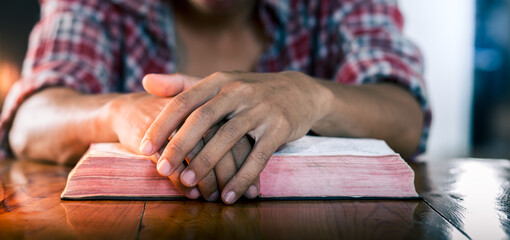 Obraz premium Hands praying of young christian man, put hands on the bible, Christian concept.