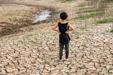 Boy in dryland looking at drought landscape. The concept for climate change from global warming. 