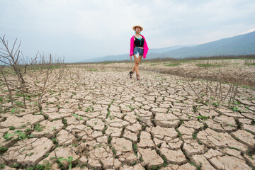 woman walking in dryland with drought ground texture. concept climate changed.