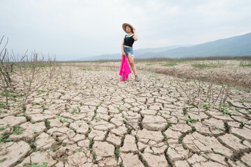 woman walking in dryland with drought ground texture. concept climate changed.