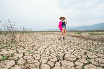 woman walking in dryland with drought ground texture. concept climate changed.