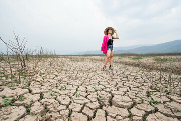 woman walking in dryland with drought ground texture. concept climate changed.