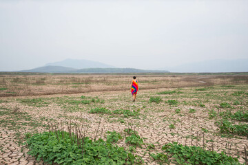 woman walking in dryland with drought ground texture. concept climate changed.