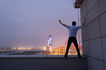 Businessman standing on the rooftop with arms raised