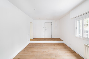 Empty room after renovation with window, white walls and wooden floor in new apartment