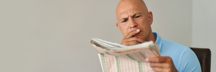 Man at home reading newspaper