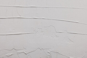 unevenly applied white putty with different defects like cracks and spatula marks