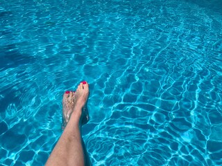 Female feet in swimming pool summer mood 