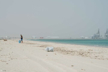 Man doing beach clean up overlooking big factory