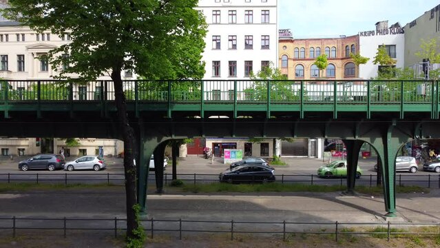 Green bridge of an elevated train. Cars driving on the road. Perfect aerial view flight stable tripod drone footage of Berlin Prenzlauer Berg Sch&ouml;nauer Allee Spring 2022. Cinematic by Philipp Marnitz