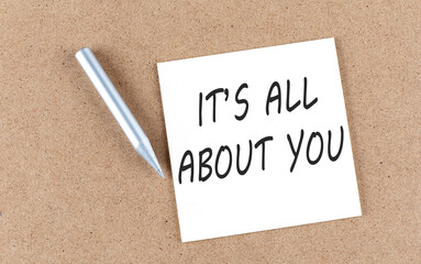 IT'S ALL ABOUT YOU text on sticky note on a cork board with pencil ,