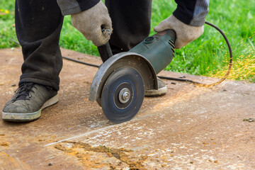 Obraz premium A man cuts metal with circular saw cutter on sheet of steel