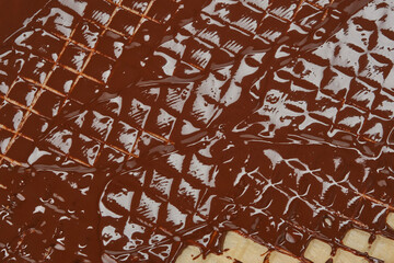 Molten chocolate flowing down a waffle sheet. Close up of the waffle sheet smeared liquid chocolate. Shallow depth of field