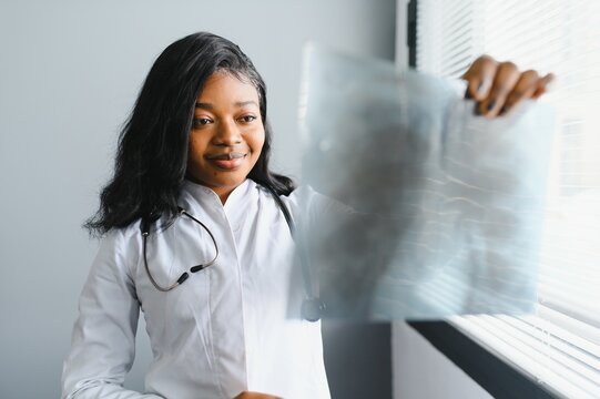 healthcare, medical and radiology concept - african doctor looking at x-rays.