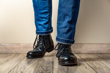 Man in black leather boots and jeans on a wooden floor