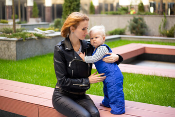 Fototapeta premium Woman hipster playing with child baby boy outdoors on urban background