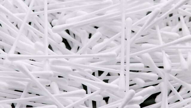 pile of q-tips or cottom buds slowly rotating on black background, loopable