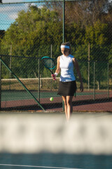 Young female caucasian athlete serving at tennis court on sunny day