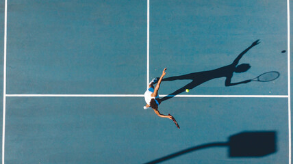 Overhead view of african american young female player serving on blue tennis court during sunny day