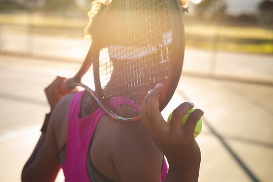 African american young female player with racket behind head at court