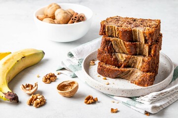 Pieces of american homemade sliced banana bread with chopped walnuts, chocolate and cinnamon. Stack of pieces of bread. Breakfast concept. Selective focus.