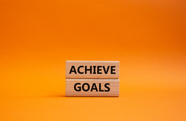 Achieve goals symbol. Concept words achieve goals on wooden blocks. Beautiful orange background. Business and achieve goals concept. Copy space.