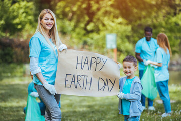 Happy volunteers holding placard with 'happy Earth day' message. Volunteer opportunities....