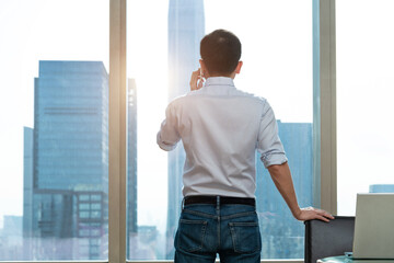 Businessman using mobile phone in front of the window