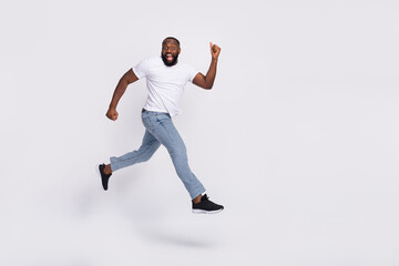 Photo of excited pretty guy dressed casual t-shirt jumping high running hurry isolated white color background