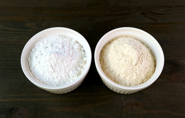 A Bowl of Refined Flour and a Bowl of Whole Wheat Flour Isolated on Black Wooden Background